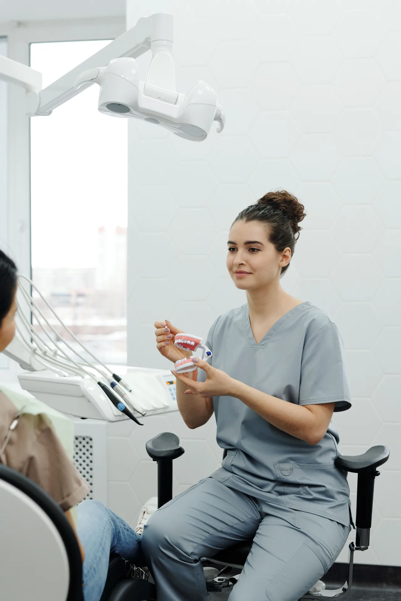Profissional de odontologia orientando paciente com modelo dental